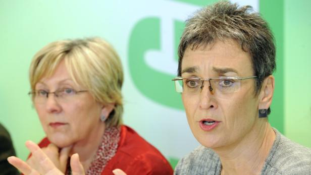 Zwei Frauen sitzen vor einem grünen Hintergrund und sprechen.