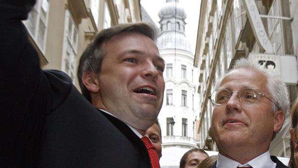 Zwei Männer in Anzügen stehen auf einer Straße in Wien.