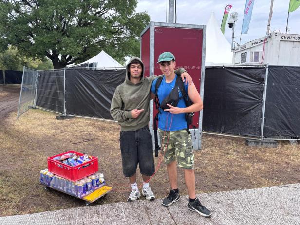 Zwei Festivalbesucher stehen neben einem mit Bierkisten beladenen Wagen.