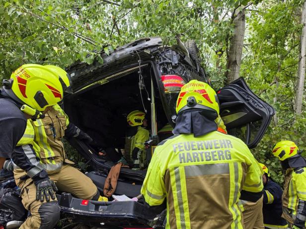 Feuerwehrleute sichern einen umgestürzten Pkw im Wald nach einem Unfall.