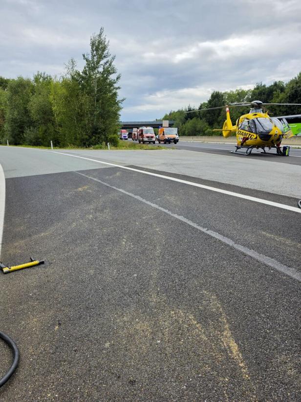 Rettungshubschrauber und Einsatzfahrzeuge stehen auf einer Autobahn nach einem Unfall.