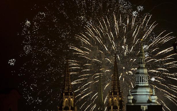 Feuerwerk über den Türmen einer Kirche bei Nacht.