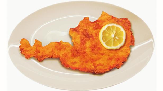 Ein Wiener Schnitzel in Form von Österreich mit einer Zitronenscheibe auf einem Teller.