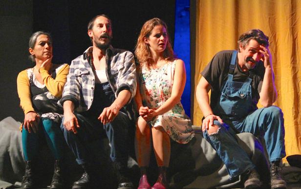 Vier Schauspieler sitzen auf einer Bühne vor einem gelben Vorhang.