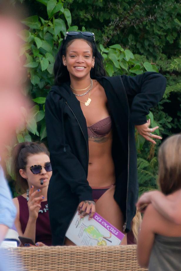 Rihanna posiert mit einem Cocktailmenü in der Hand.