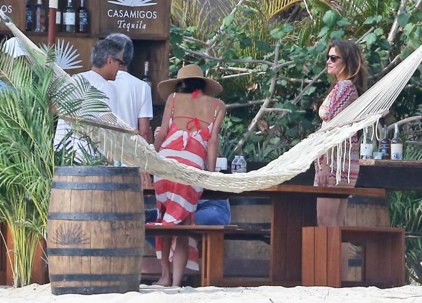 Menschen entspannen am Strand an einer Bar mit Casamigos Tequila-Werbung.