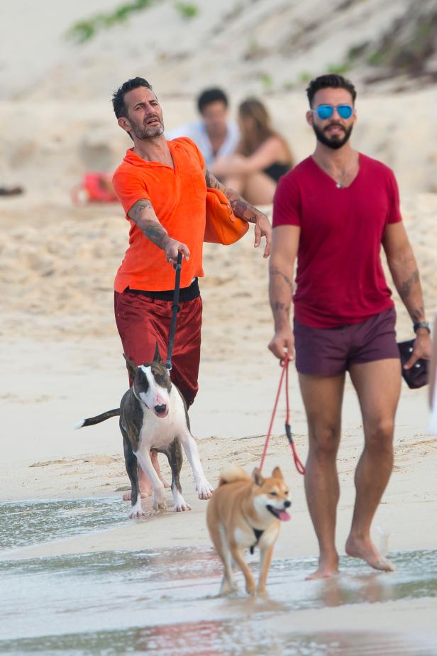 Zwei Männer führen ihre Hunde am Strand spazieren.