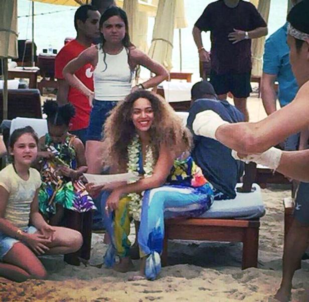 Beyoncé sitzt mit Kindern und anderen Personen am Strand.