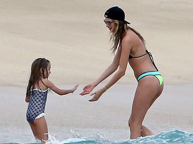 Cara Delevingne spielt mit einem kleinen Mädchen am Strand.