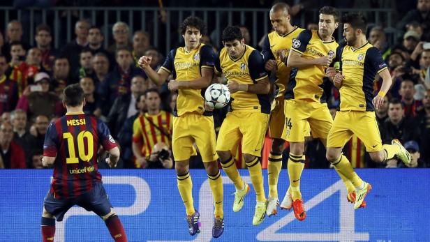 Lionel Messi steht vor einer springenden Mauer von Atlético Madrid während eines Fußballspiels.