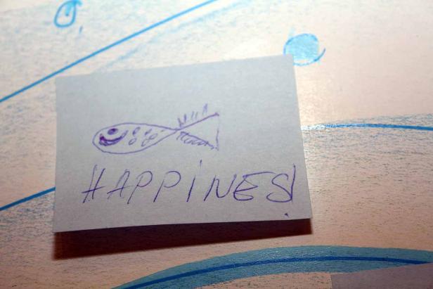 Ein Zettel mit einer Zeichnung eines Fisches und dem Wort „Happiness!“.