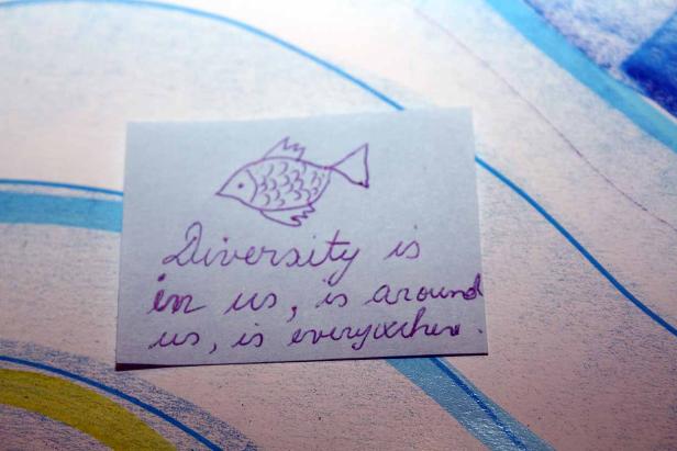 Eine Notiz mit einer Fischzeichnung und dem handgeschriebenen Text „Diversity is in us, is around us, is everywhere.“.