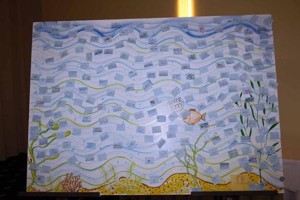 Eine Zeichnung einer Unterwasserwelt mit vielen kleinen Zetteln mit Fischzeichnungen darauf.