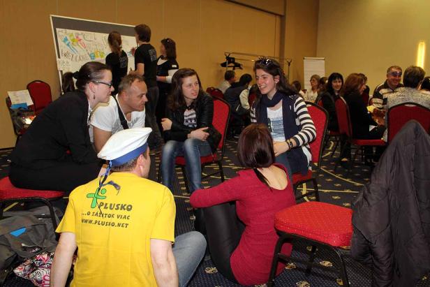 Eine Gruppe von Menschen sitzt und steht in einem Raum und unterhält sich.