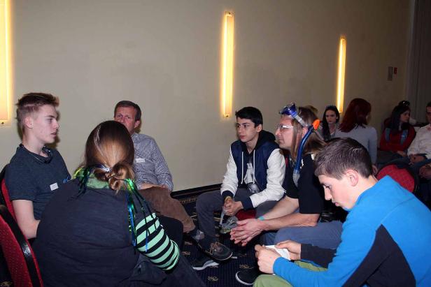 Eine Gruppe von Menschen sitzt in einem Raum und unterhält sich.