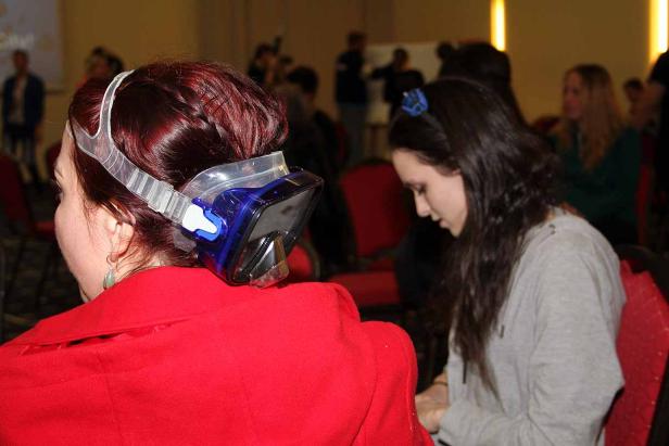 Eine Frau mit einer Tauchmaske auf dem Hinterkopf sitzt in einem Publikum.