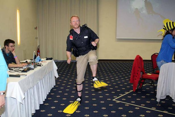 Ein Mann mit Tauchausrüstung und gelben Schwimmflossen posiert in einem Raum.