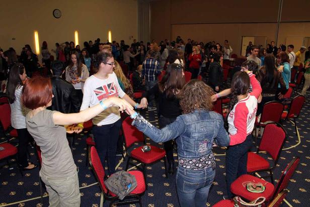 Eine Gruppe von Menschen tanzt im Kreis in einem großen Raum.