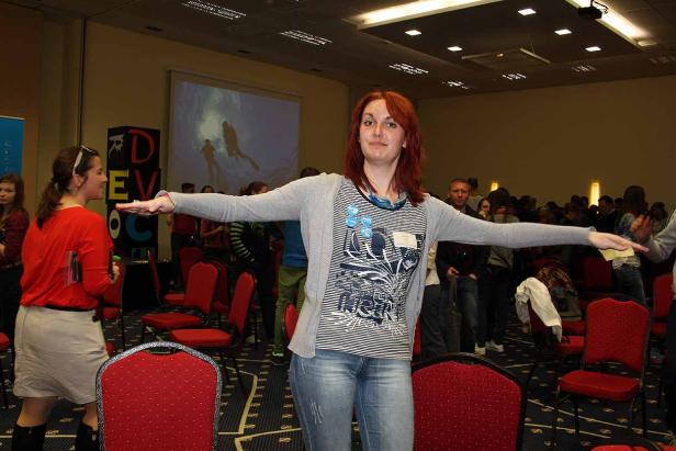 Eine Frau steht mit ausgestreckten Armen in einem Raum voller Menschen.