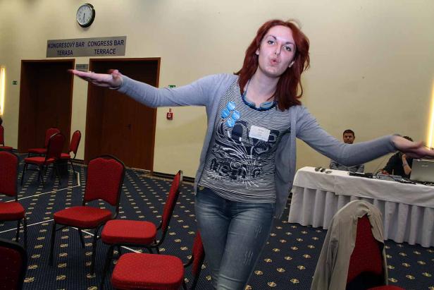 Eine Frau mit roten Haaren posiert in einem Konferenzraum mit roten Stühlen.