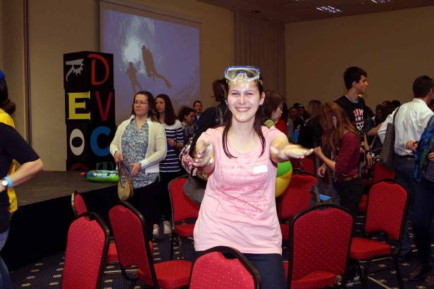 Eine junge Frau mit Taucherbrille auf dem Kopf steht in einem Konferenzraum.