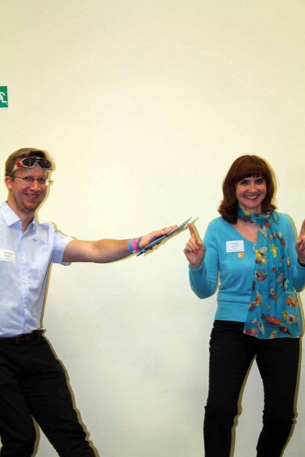 Ein Mann mit Sonnenbrille auf dem Kopf und eine Frau mit einem bunten Schal posieren für ein Foto.