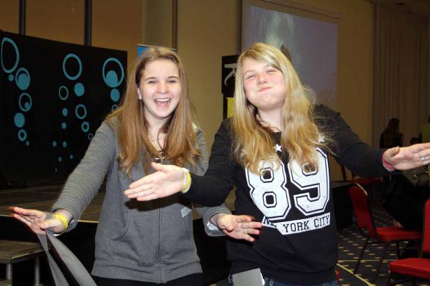 Zwei junge Frauen stehen nebeneinander und lächeln in die Kamera.