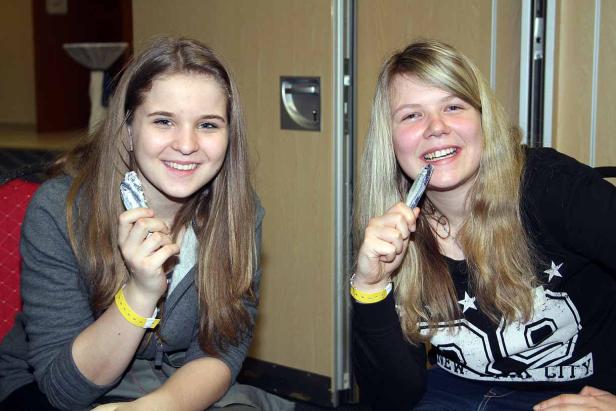 Zwei junge Frauen lächeln und halten jeweils eine Sardine in der Hand.