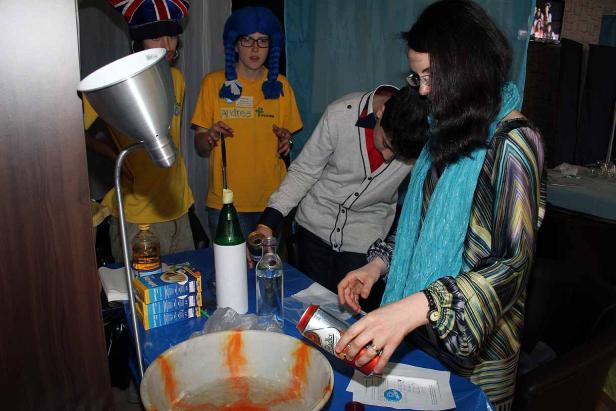 Mehrere Personen stehen um einen Tisch mit Getränken und einer Schüssel mit Flüssigkeit.