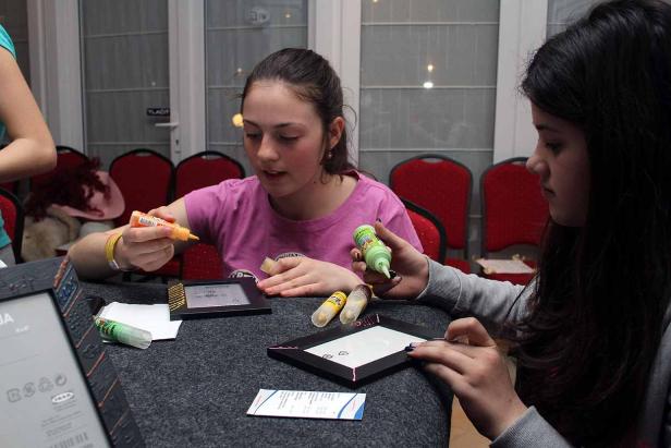 Zwei junge Frauen verzieren Bilderrahmen mit Farbe.