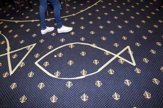 Ein Fischsymbol ist mit Klebeband auf einem Teppich dargestellt.