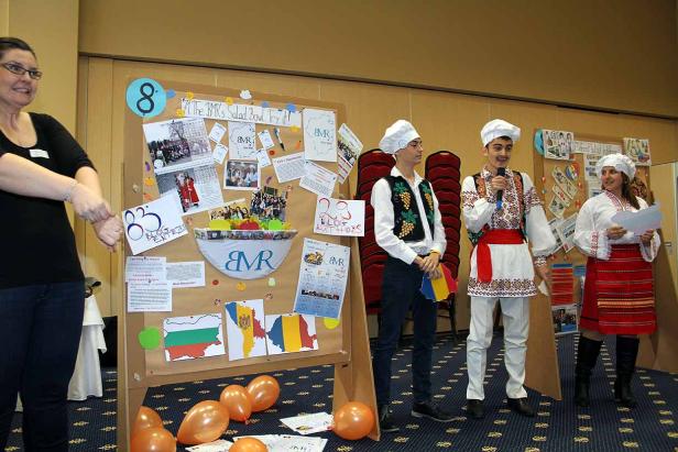 Eine Gruppe von Personen in Trachten steht vor einer Präsentationstafel.