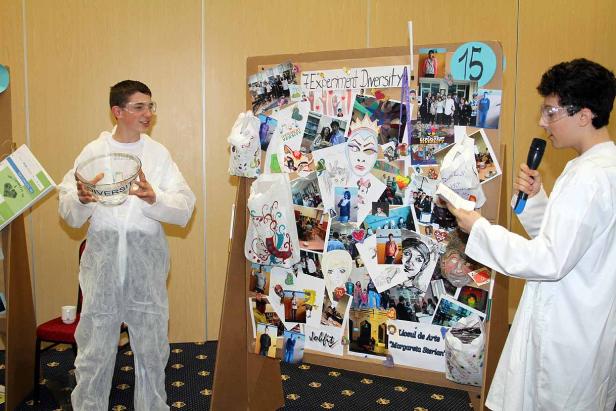 Zwei Jugendliche in Laborkitteln präsentieren ein Projekt zum Thema Diversität.