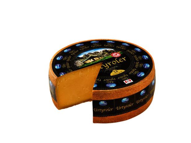Ein angeschnittener „Urtyroler“-Käse liegt auf einem weißen Hintergrund.