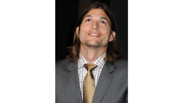 Ashton Kutcher in einem grauen Anzug blickt nach oben.