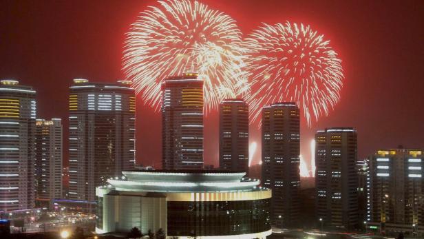 Feuerwerk erhellt den Himmel über einer Stadt mit modernen Hochhäusern.