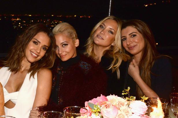 Jessica Alba, Nicole Richie, Kate Hudson und eine weitere Frau sitzen an einem Tisch mit Blumen und Kerzen.