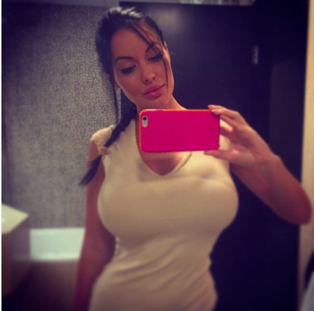 Eine Frau macht ein Selfie mit einem pinkfarbenen Handy vor einem Spiegel.