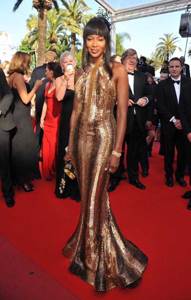 Naomi Campbell in einem goldenen Paillettenkleid auf einem roten Teppich.
