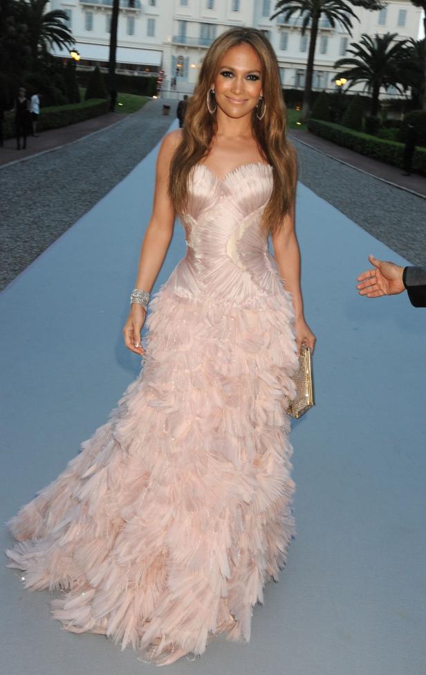 Jennifer Lopez in einem rosa Federkleid auf einem roten Teppich.