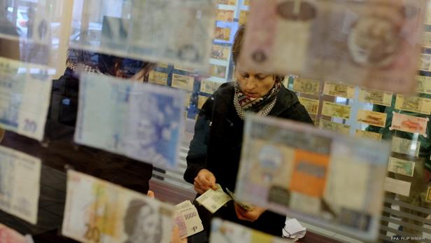 Eine Frau betrachtet Geldscheine aus aller Welt in einer Ausstellung.