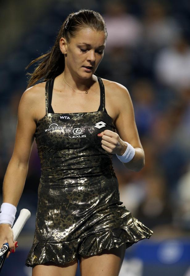 Eine Tennisspielerin in einem goldenen Kleid auf dem Platz.