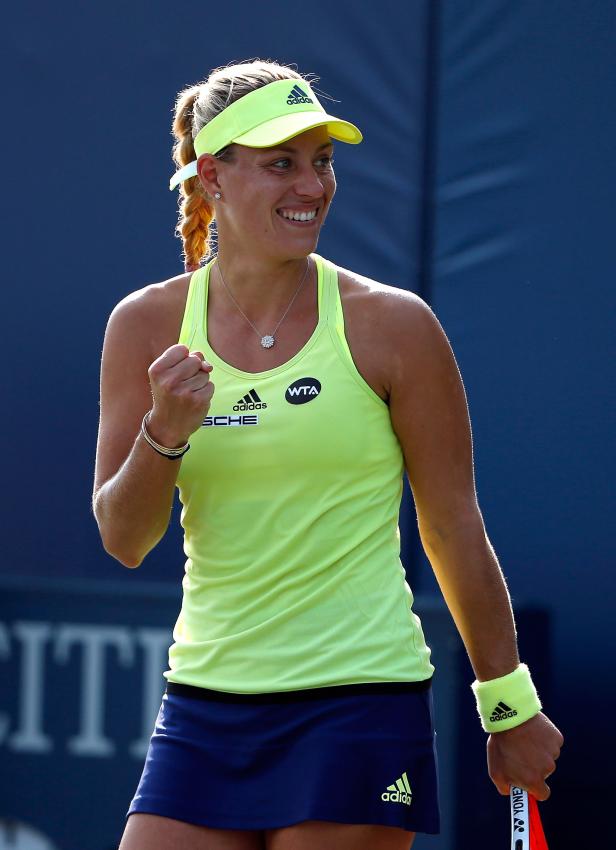 Eine lächelnde Tennisspielerin mit geballter Faust auf dem Platz.