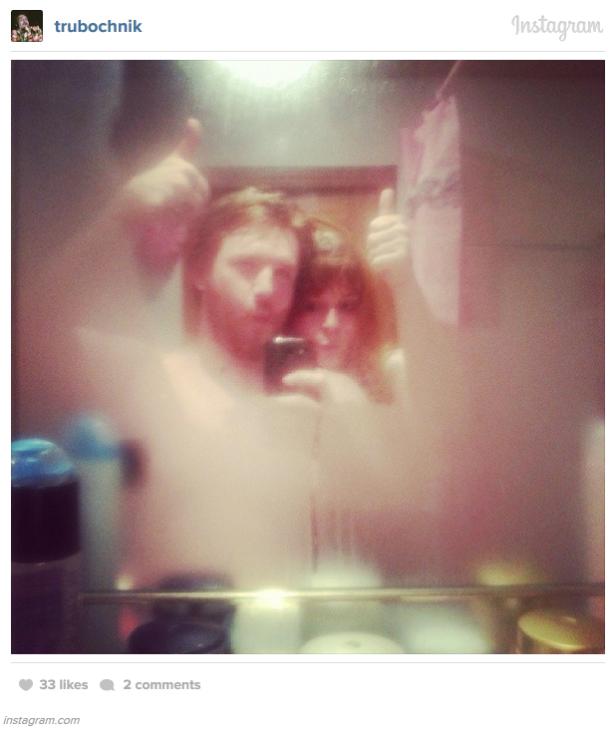 Ein Paar macht ein verschwommenes Selfie im Badezimmer mit erhobenem Daumen.