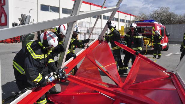 Feuerwehrleute beseitigen Sturmschäden in Wiener Neudorf im März Feuerwehrleute üben mit hydraulischem Rettungsgerät an einem roten Objekt.