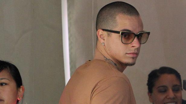 Ein Mann mit Sonnenbrille und Ohrring blickt über seine Schulter.