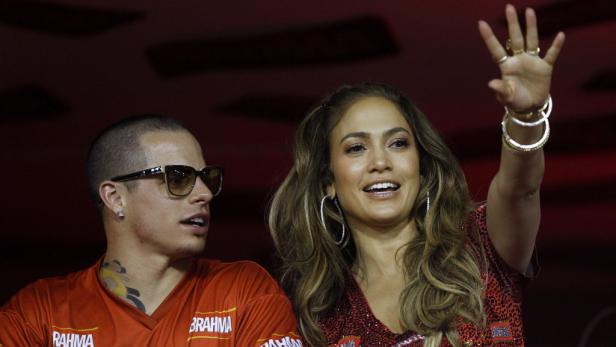 Jennifer Lopez und ein Mann in einem roten T-Shirt winken in die Menge.