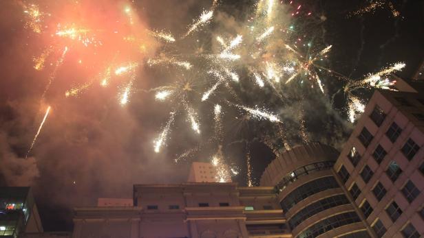 Feuerwerk erhellt den Nachthimmel über Gebäuden.