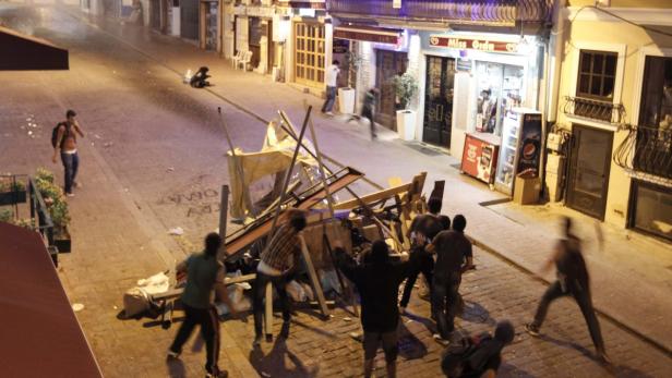 Auf einer Straße bauen Menschen eine Barrikade aus Holz und anderen Materialien.