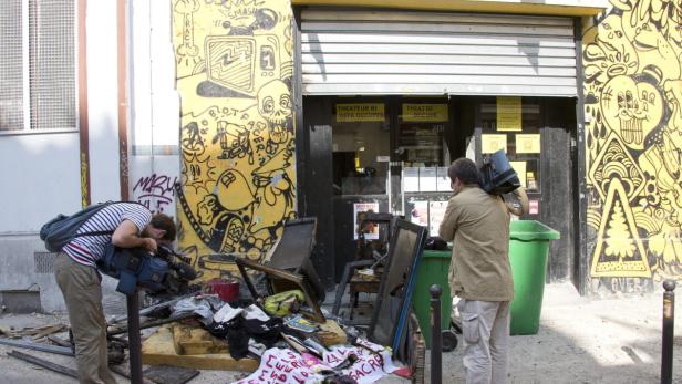 Zwei Kameraleute filmen die Überreste eines ausgebrannten Theaters mit Graffiti an den Wänden.